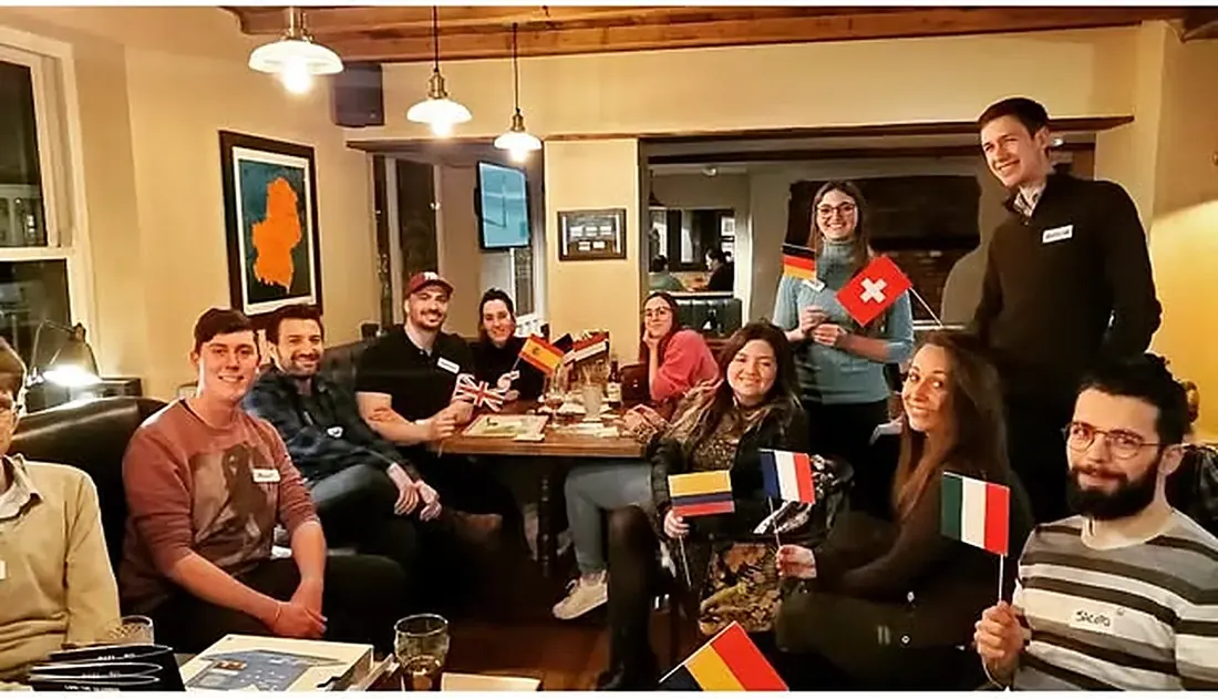 A Guildford Babel evening: a group around a pub table, holding flags of the languages they speak